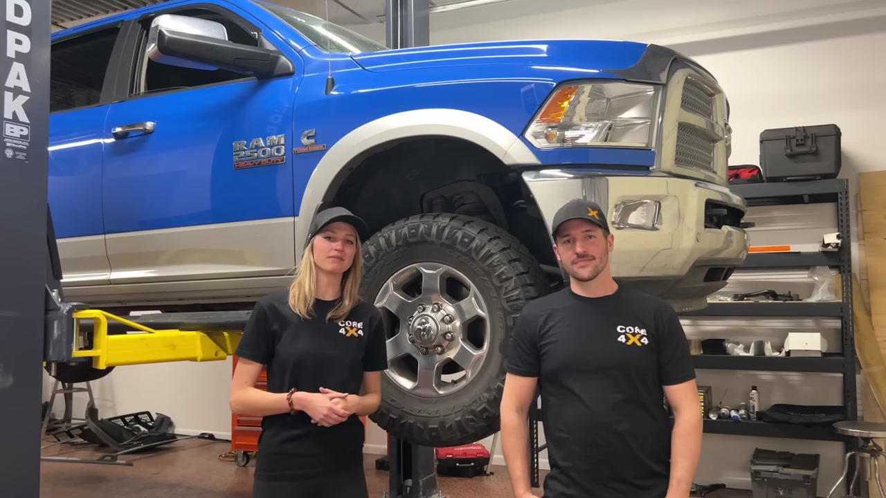 Gabian and Spence from Core 4x4 standing in front of a blue Ram 2500 on the shop lift