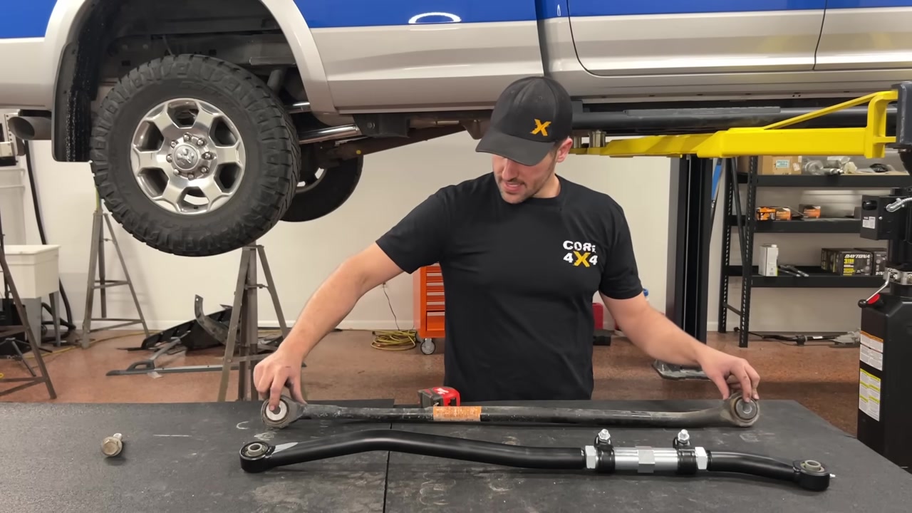 Spence at the workbench comparing the factory track bar to the new Core 4x4 adjustable track bar and setting the length