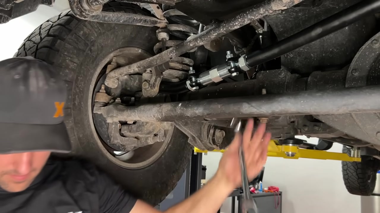 Close-up of the installed Core 4x4 Tow Series track bar on the Ram 2500 front axle showing the turnbuckle adjuster and clamps in place