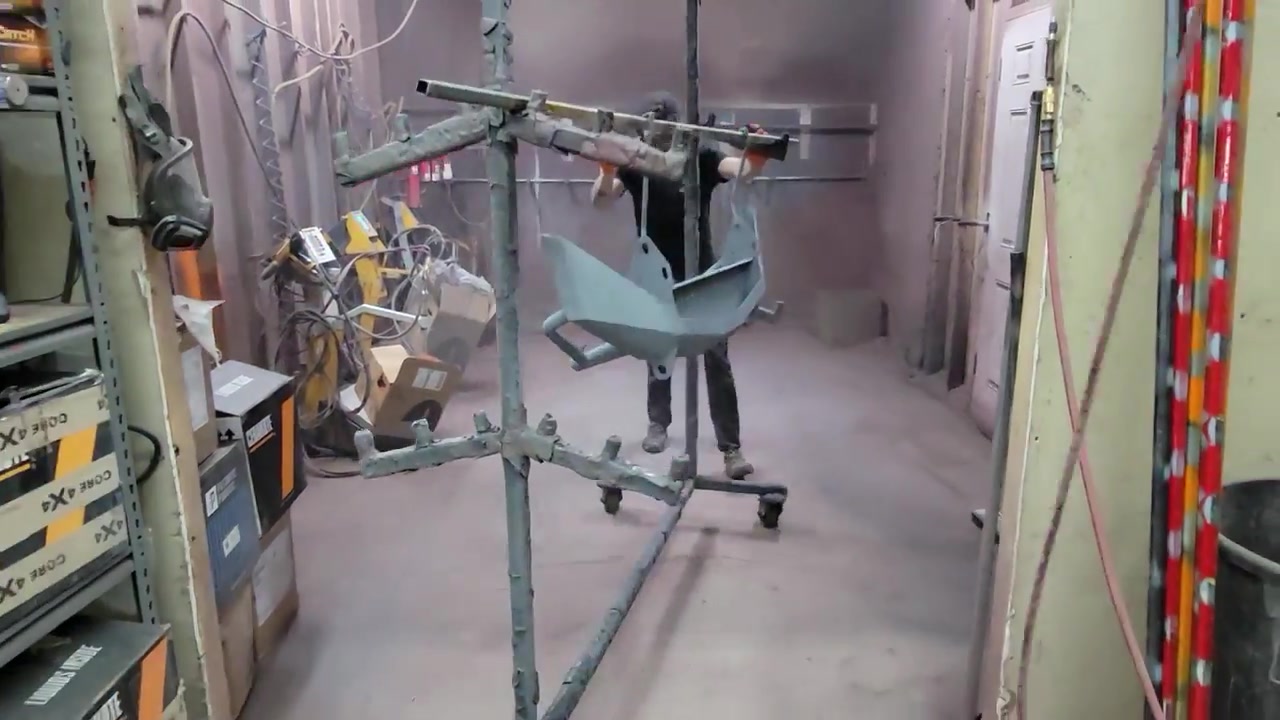 Applying powder coat to the Dirtbound bumper bracket hanging on a rack inside the Core 4x4 powder coating booth
