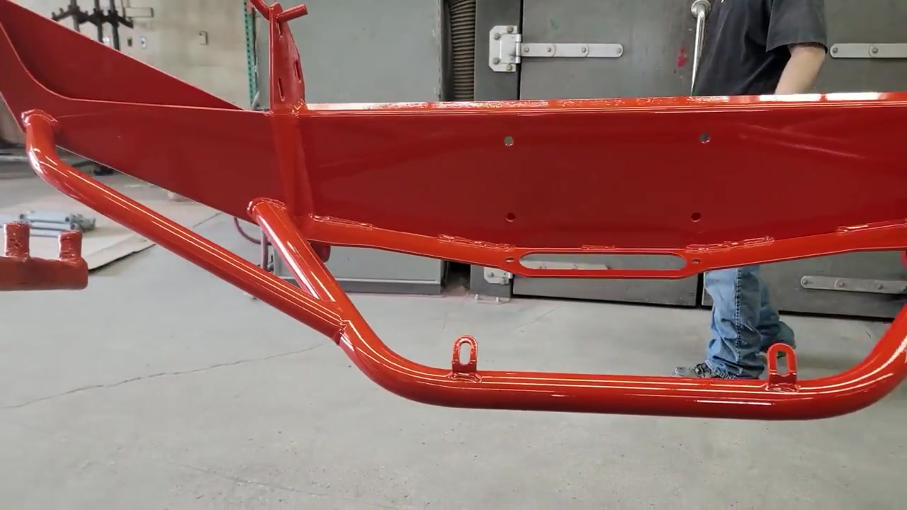 Close-up of the orange powder-coated Dirtbound front bumper and frame brace brackets fresh out of the oven