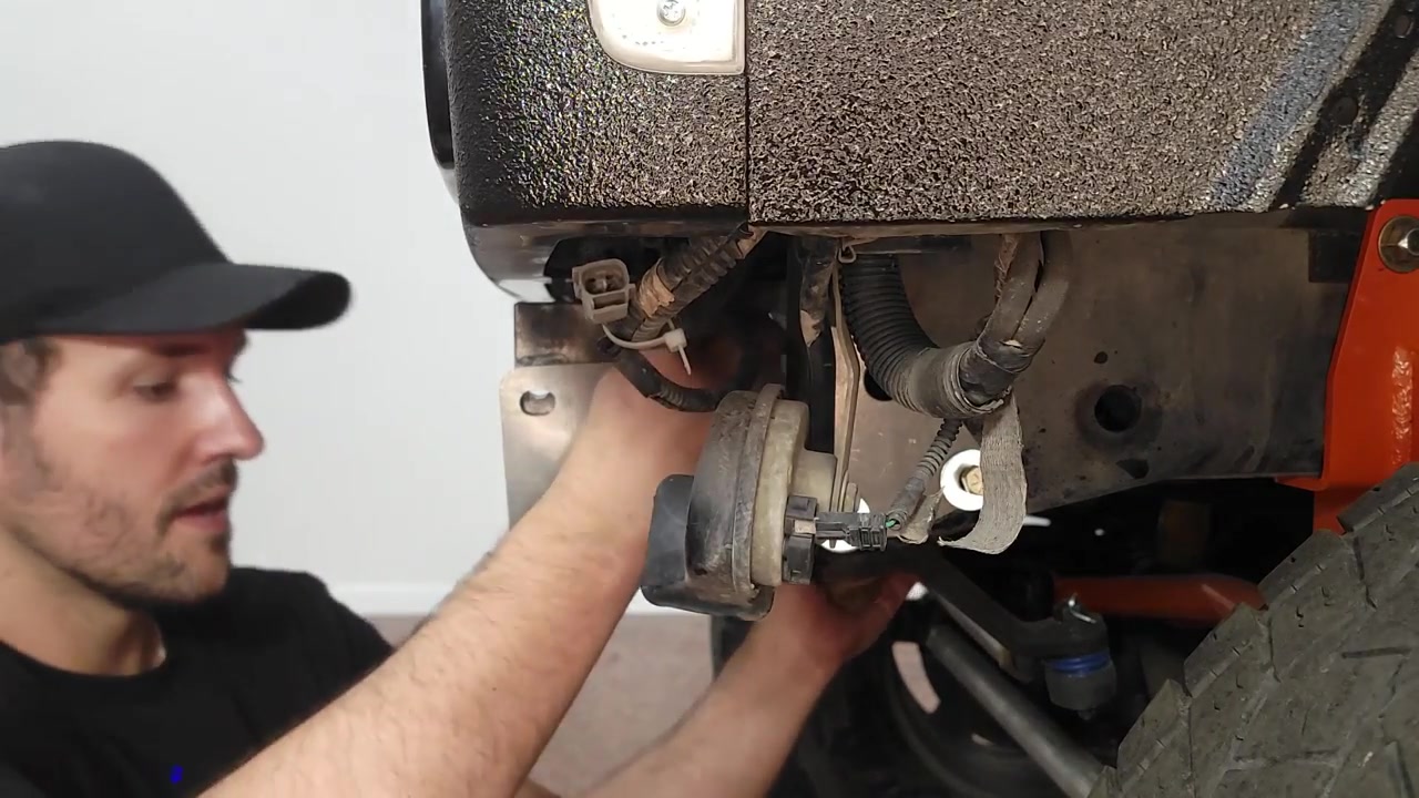 Spence installing the Dirtbound frame brace bracket underneath the XJ Cherokee near the steering box mount