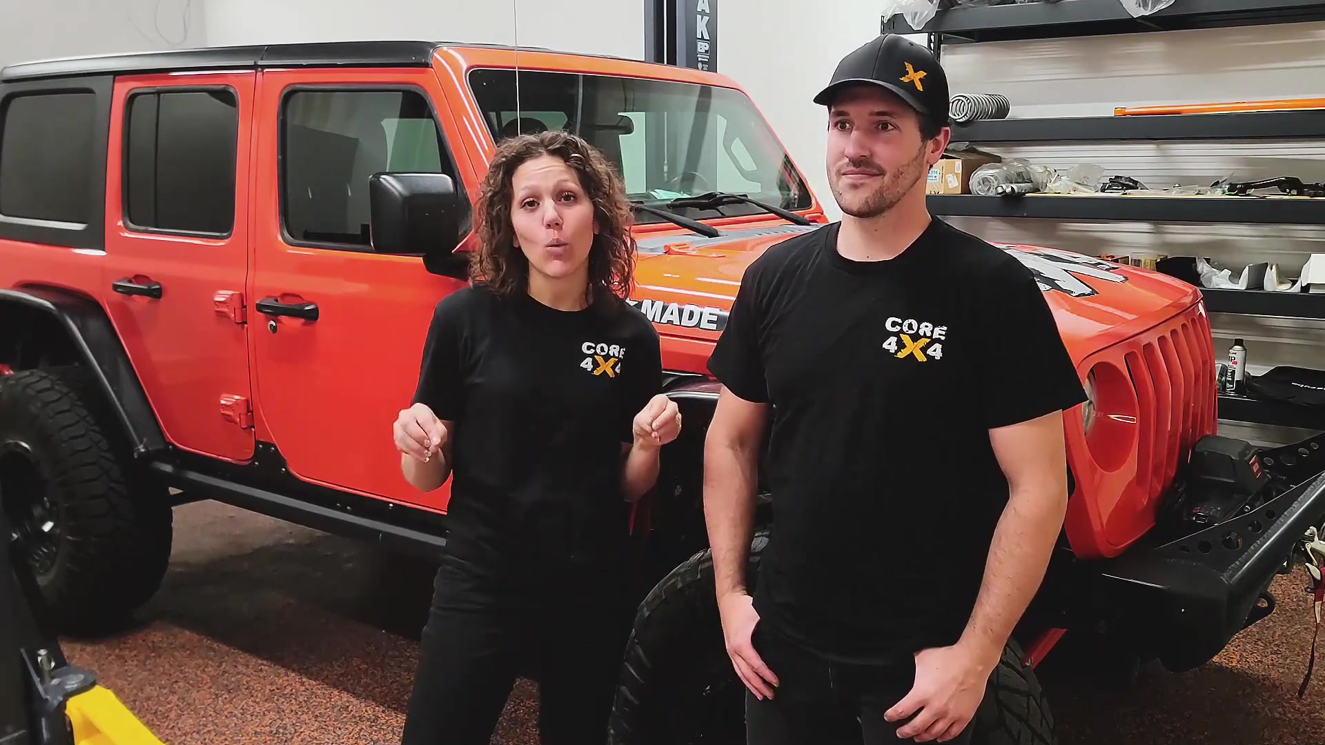 Spence and Marissa from Core 4x4 standing in front of a red Jeep Wrangler JL in the shop
