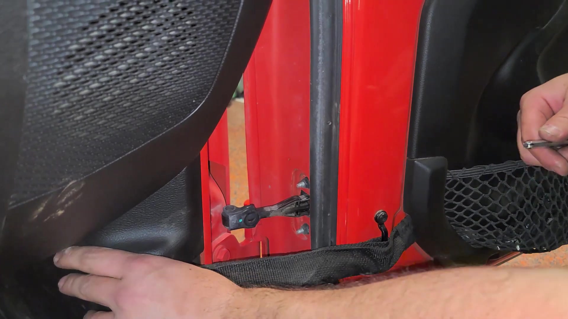 Close-up of the door check bolt and retainer strap inside the JL Wrangler door jamb