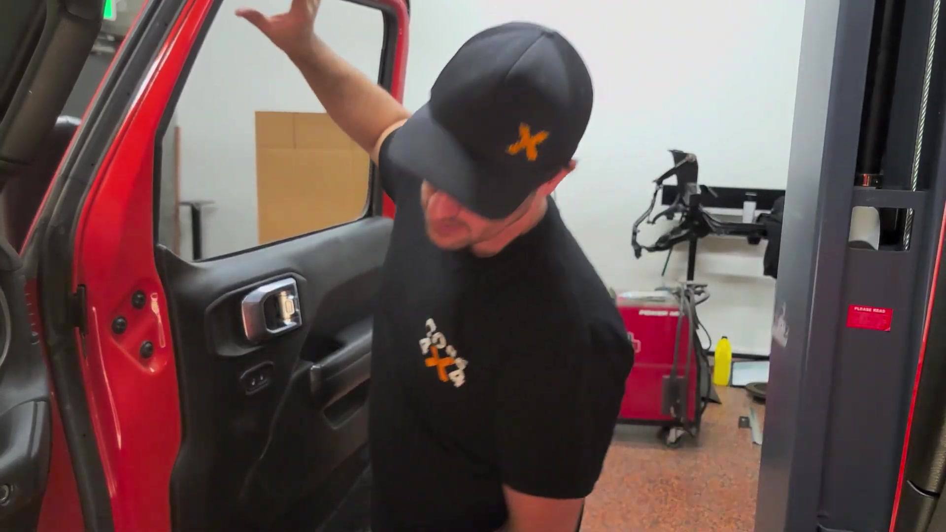 Spence lifting the front door off the red Jeep JL Wrangler in the Core 4x4 shop