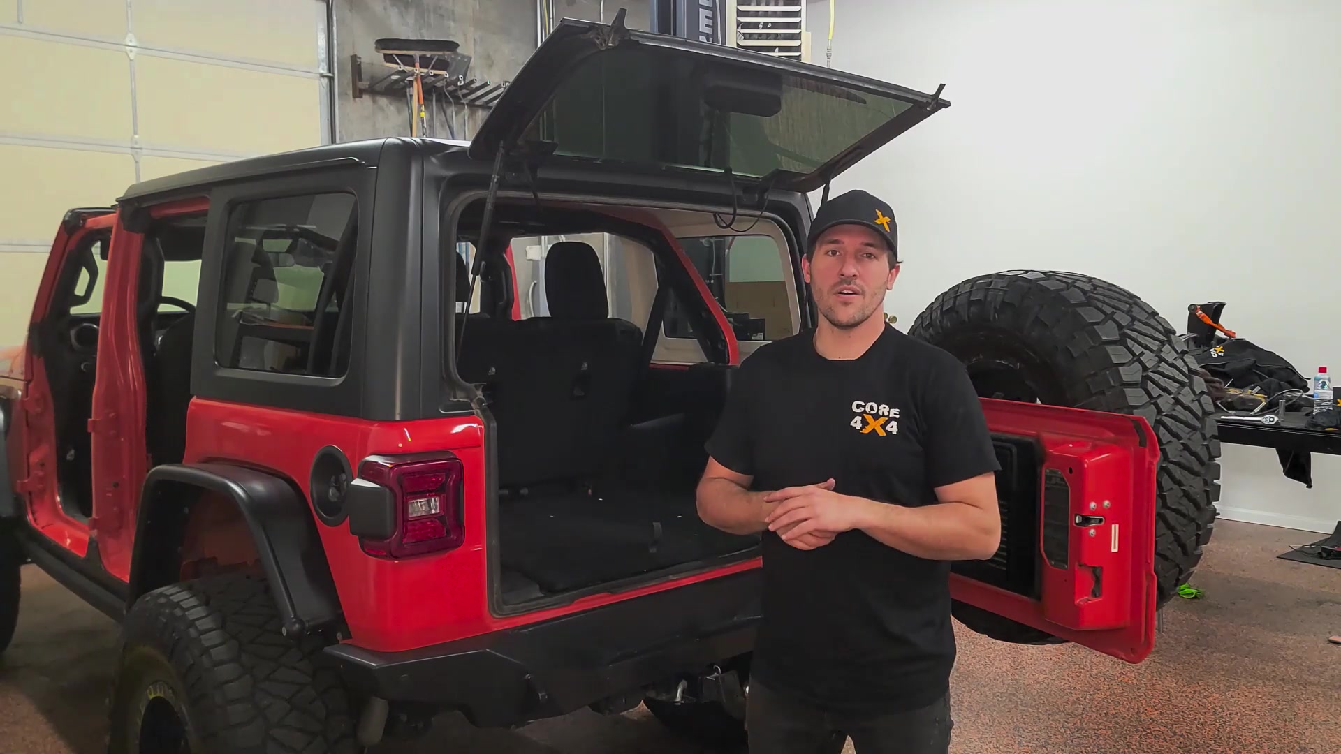 Red Jeep JL Wrangler from the rear with doors off and hardtop about to be removed