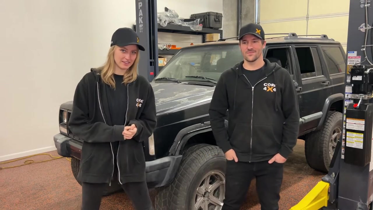 Gabby and Spence from Core 4x4 standing in front of the lifted XJ Cherokee project in the shop