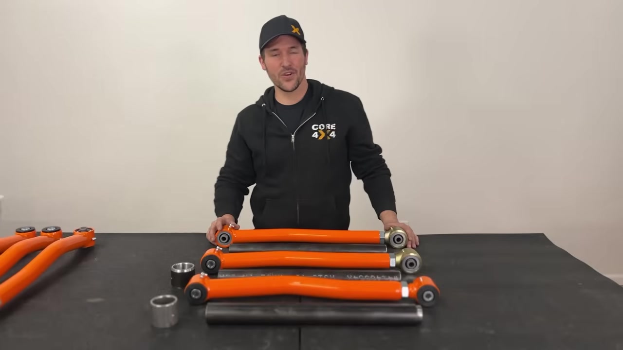 Spence from Core 4x4 standing behind three tiers of control arms laid out on a table -- Town, Trail, and Track series