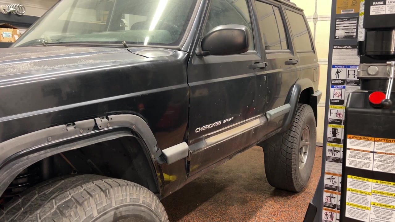 Side view of the XJ Cherokee showing faded paint, sun damage, and Cherokee Sport lettering before Rhino line