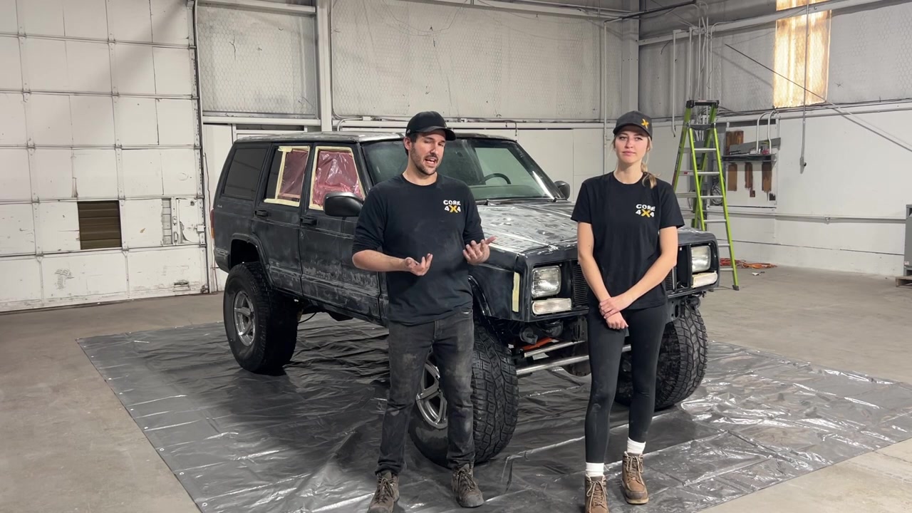 Spence and Gabby standing in front of the sanded and masked XJ Cherokee on a tarp in the warehouse ready for coating