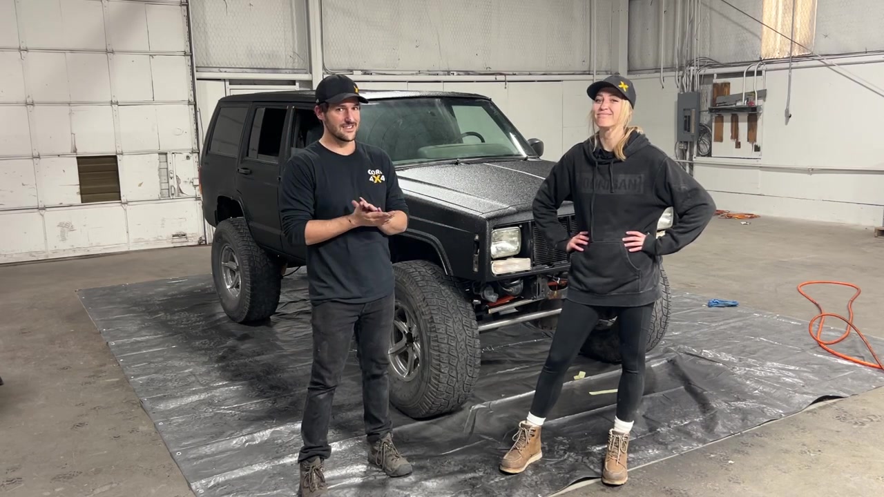 Spence and Gabby with the finished Rhino-lined XJ Cherokee showing the textured black finish in the warehouse