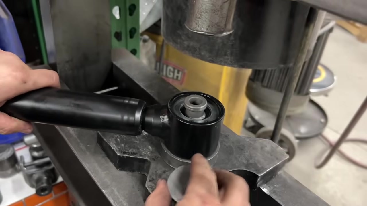 Close-up of a polyurethane bushing being pressed into a control arm housing in the Core 4x4 shop