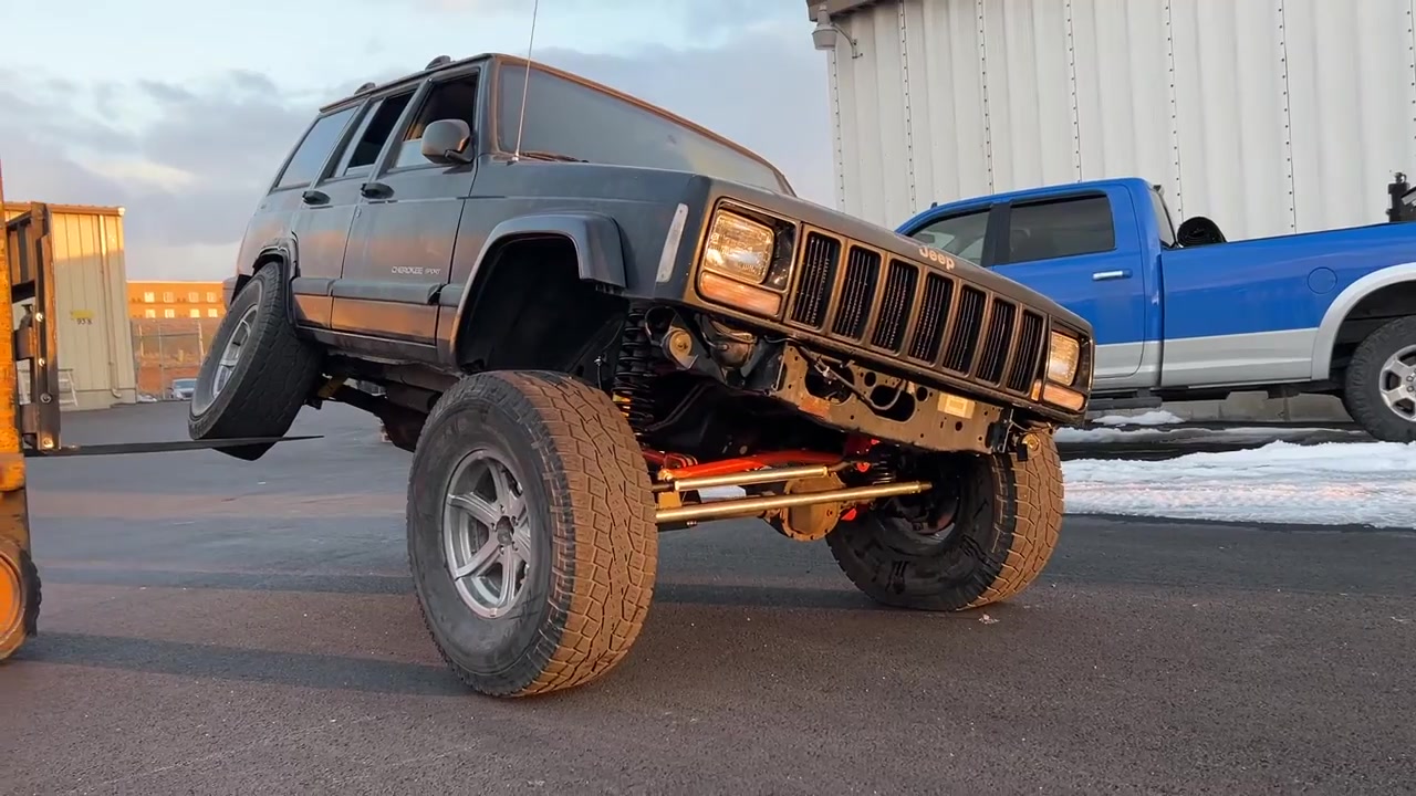 XJ Cherokee flexed at golden hour outside the Core 4x4 shop with lifted suspension and 35-inch tires visible