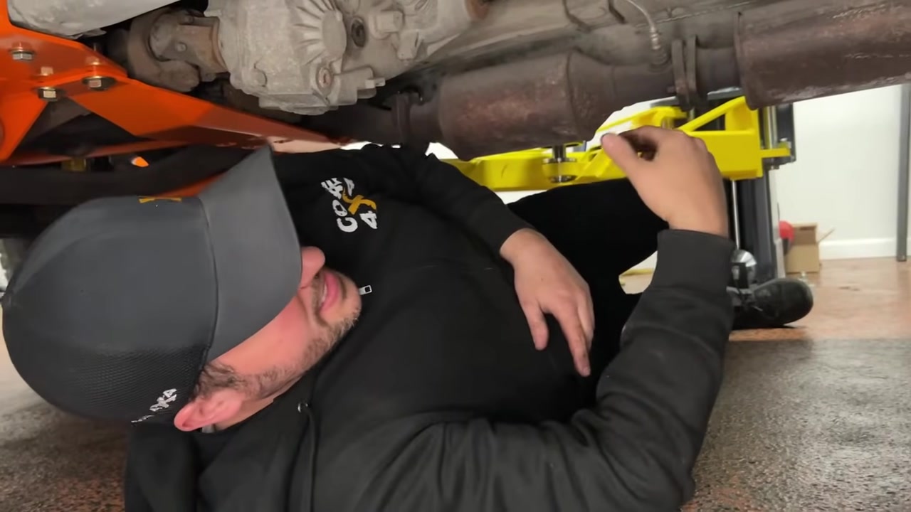 Cutting the transfer case output shaft with a cutting wheel, sparks visible under the XJ Cherokee