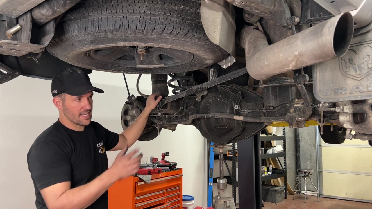 Spence under the Ram 2500 bolting in a new Core 4x4 Aluminum Series lower rear control arm with the axle supported on the lift