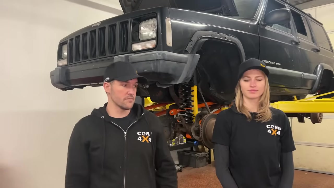 Spence and Gabby discussing the WJ knuckle swap components with the XJ Cherokee on the lift behind them