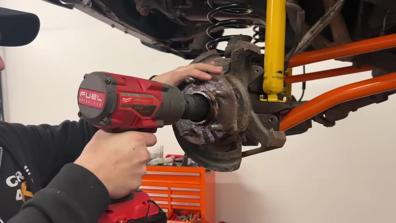 Using a Milwaukee impact wrench to remove the axle nut from the XJ Cherokee hub during WJ knuckle swap teardown