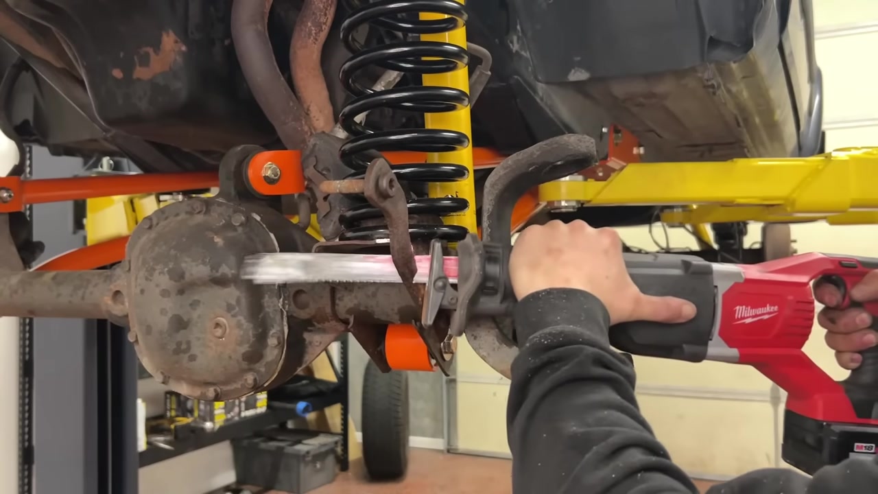 Using a reciprocating saw to trim the factory sway bar and end link mounts off the XJ Cherokee Dana 30 axle for the WJ knuckle swap