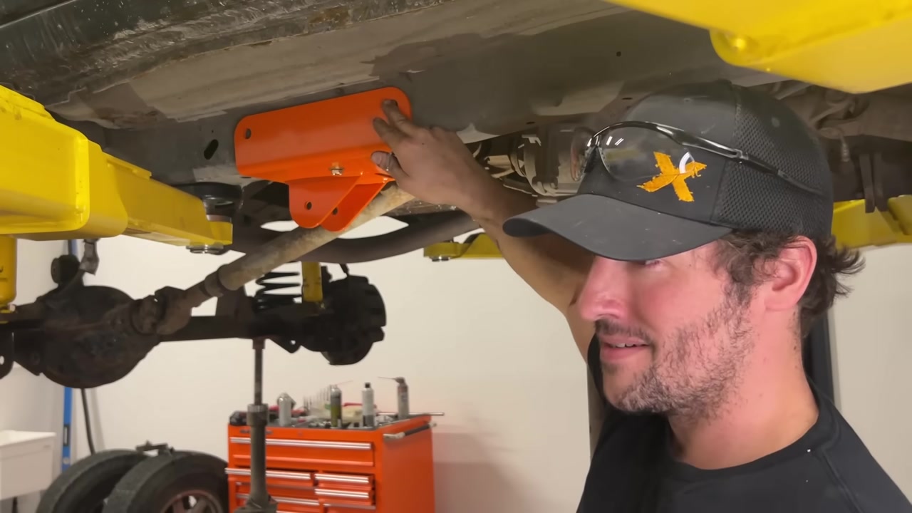 Spence showing the orange Core 4x4 frame bracket bolted to the XJ Cherokee unibody