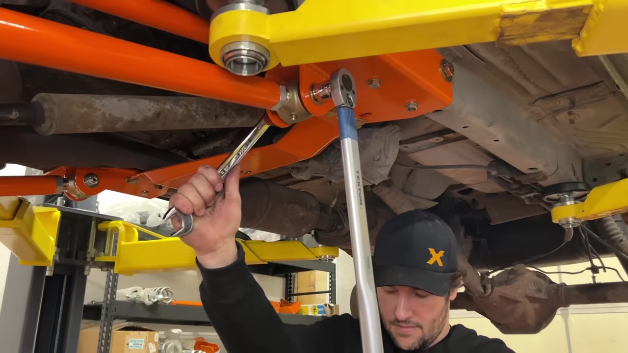 Spence torquing bolts on the installed orange Core 4x4 long arms under the XJ Cherokee