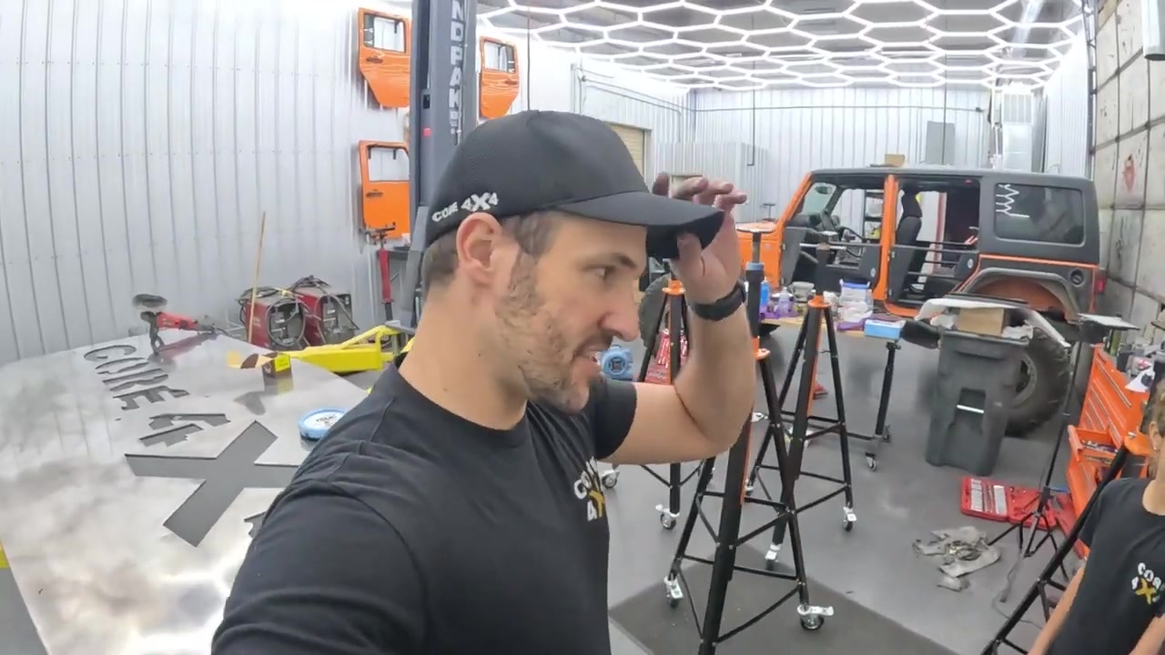 Spence in the Core 4x4 studio with finished black powder-coated jack stands visible behind him alongside the orange Jeep