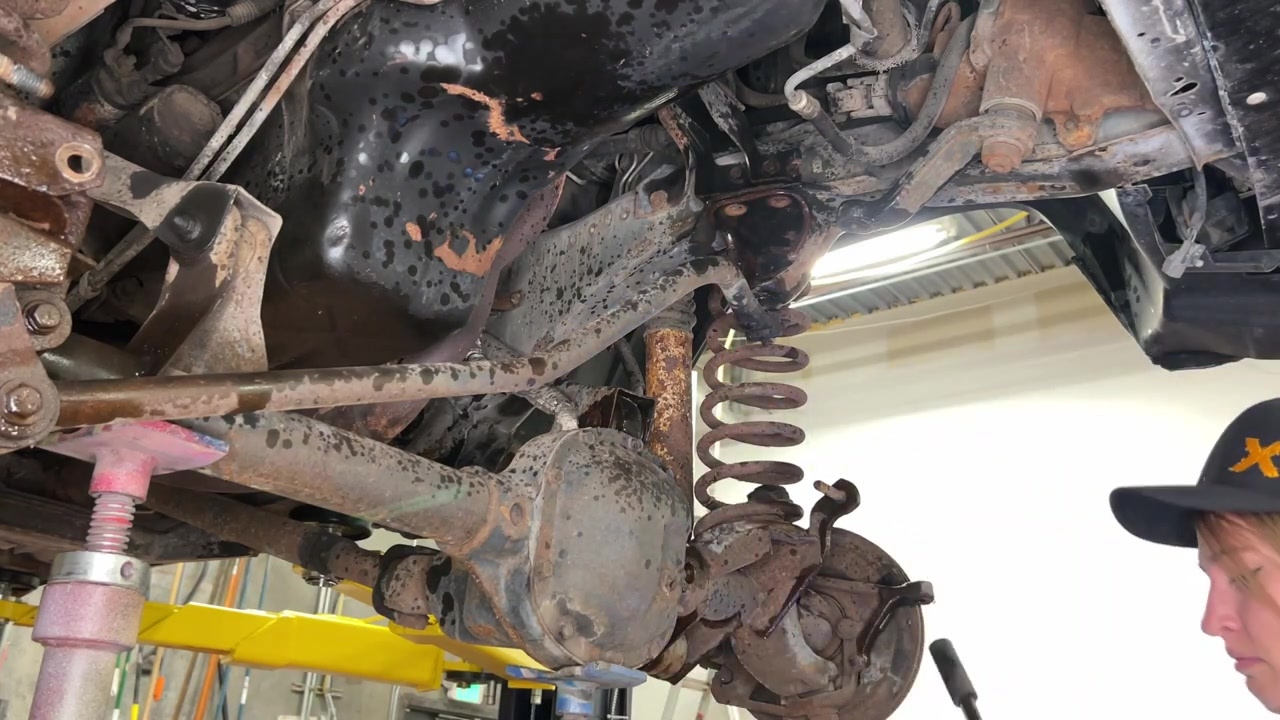 Close-up of rusty XJ Cherokee front suspension showing corroded control arms, springs, and coil mount