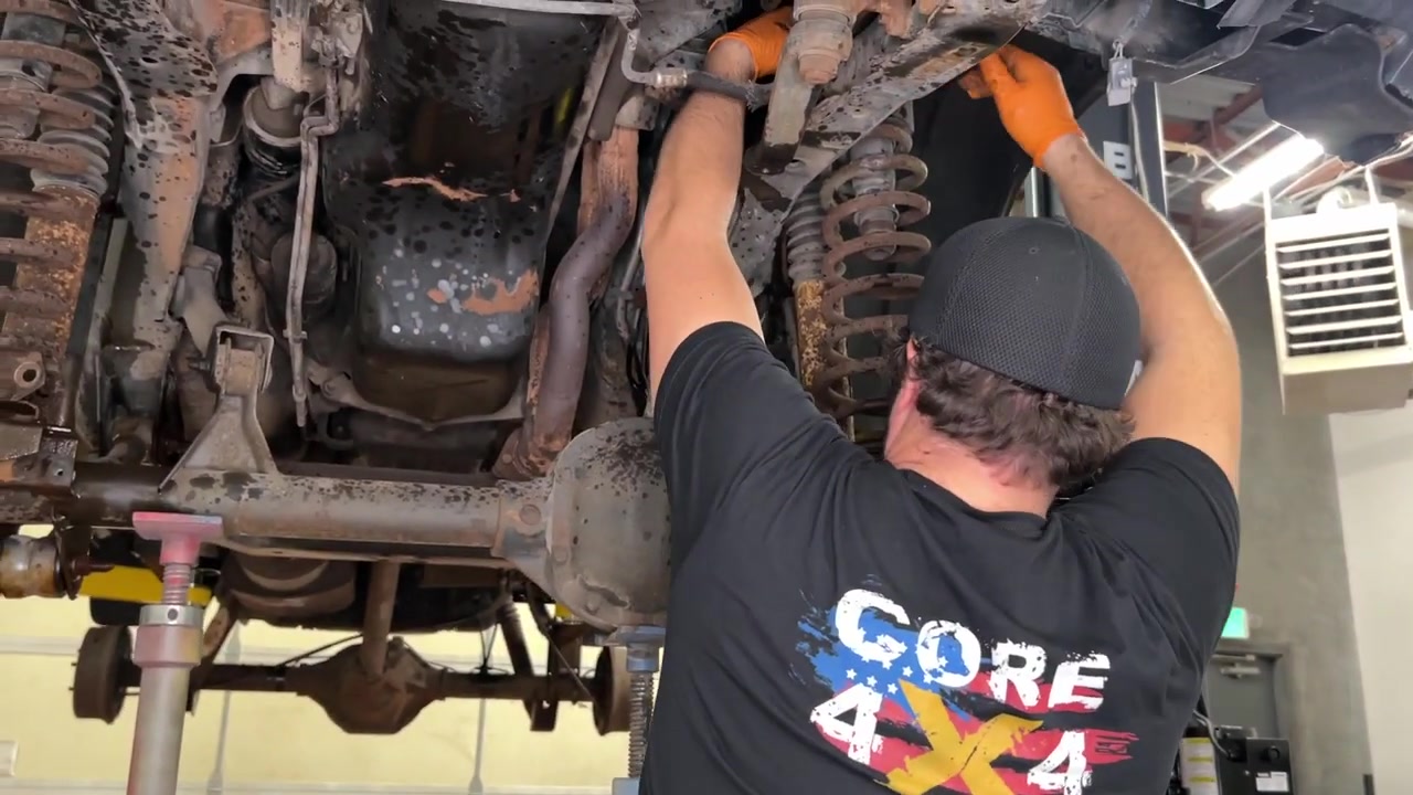 Spence removing front suspension components from the XJ Cherokee with the axle supported on the lift