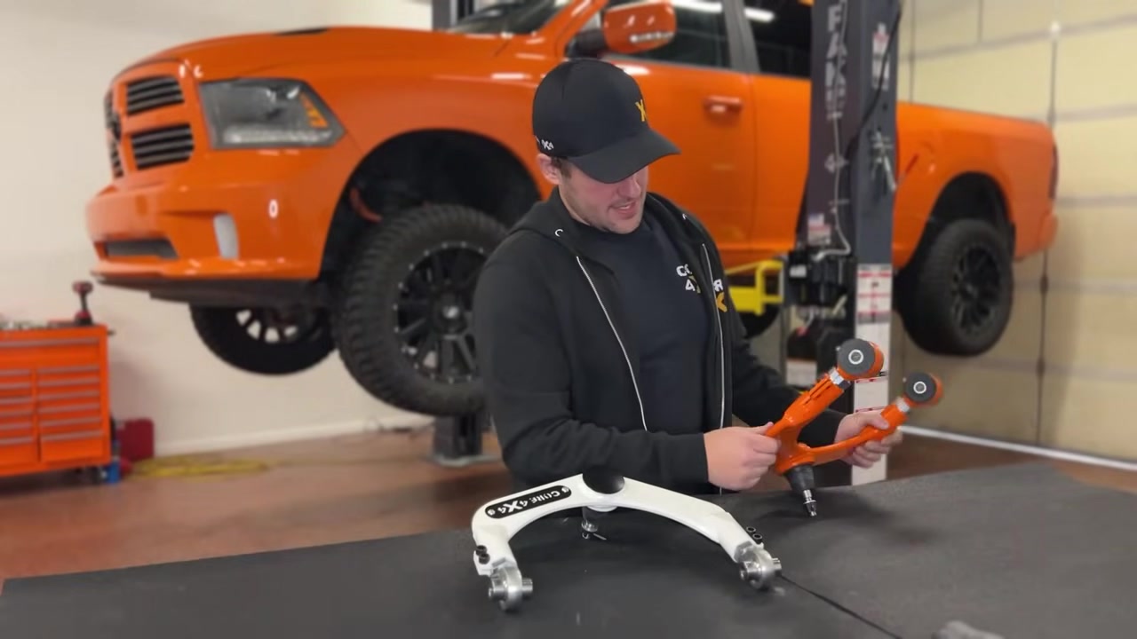 Spencer presenting the Core 4x4 adjustable upper control arm, showing the laser-cut half-inch plate steel construction and CNC machined adjustment sleeves