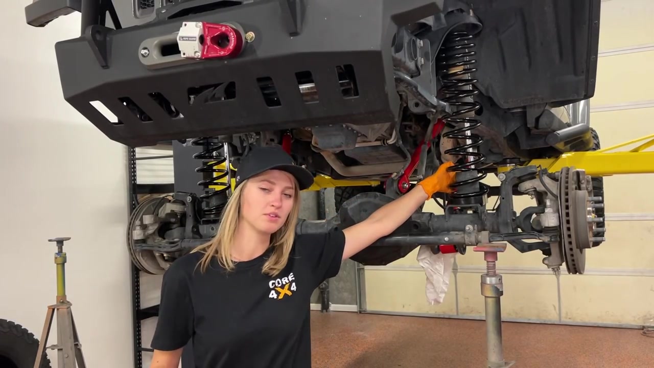 Gabby working underneath the JL Wrangler installing taller coil springs during the lift upgrade