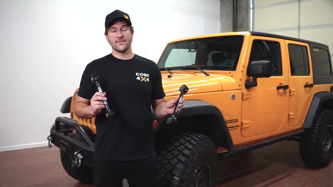 Close-up of Core 4x4 crawler series sway bar end links with Johnny Joints and black anodized finish held in front of the JK Wrangler