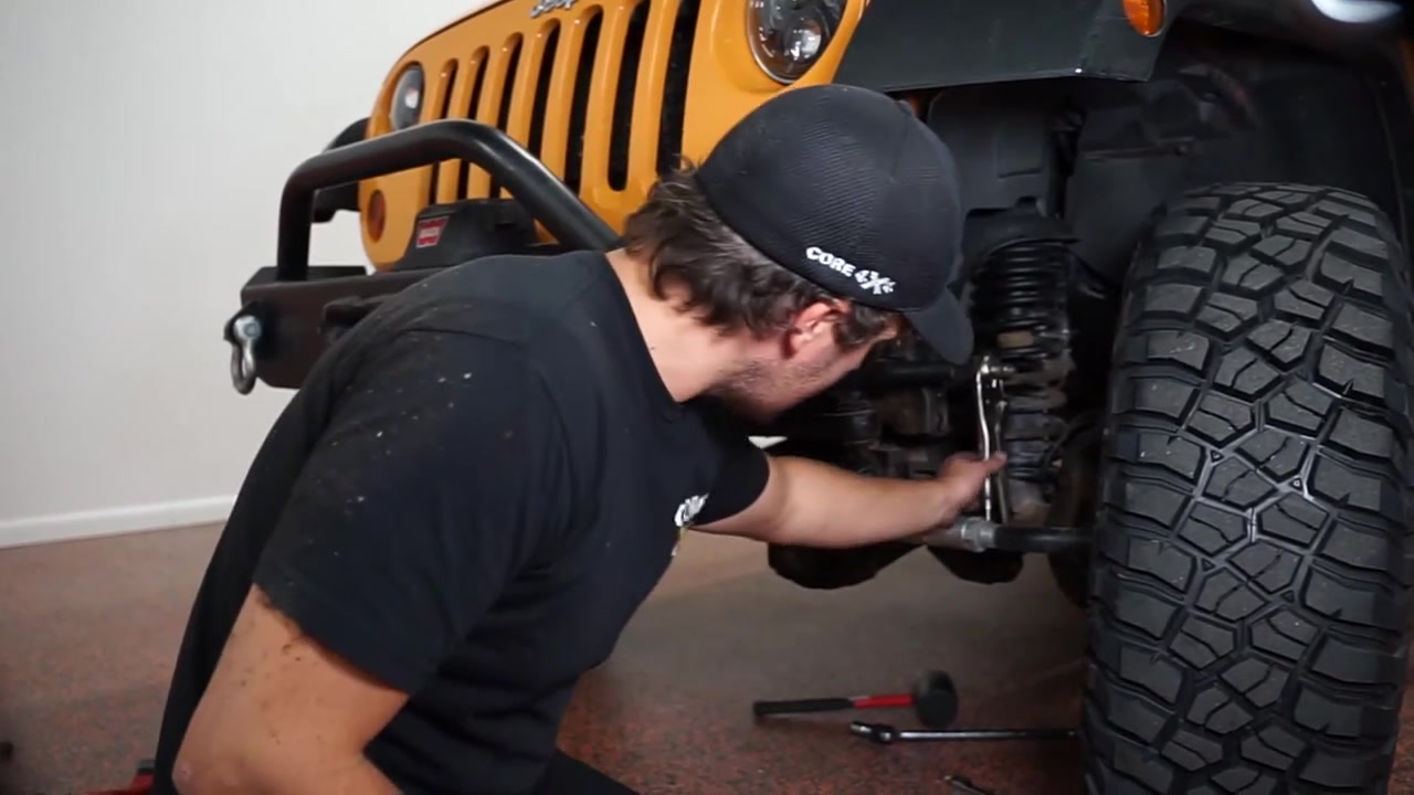 Spence removing the seized factory sway bar end link hardware from the JK Wrangler front axle using hand tools