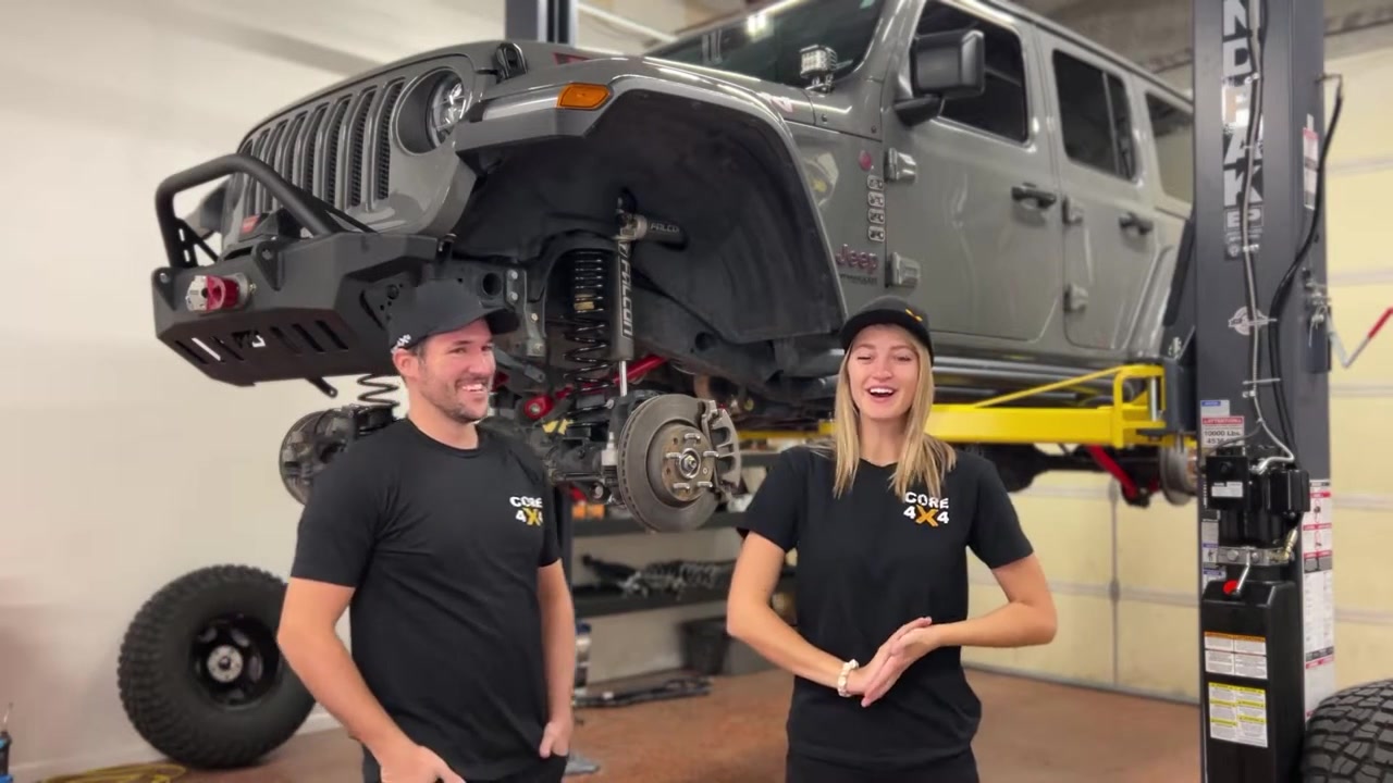 Spence and Gabby in front of JL Wrangler on lift with red Core 4x4 Crawl Series components visible