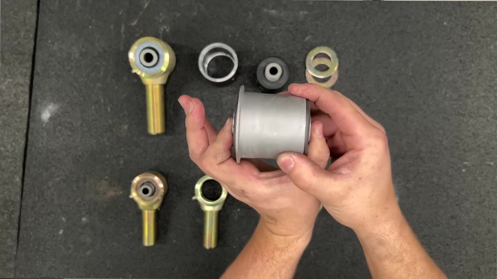 Overhead view comparing a factory rubber bushing with fused crush sleeve to Johnny Joint components including ball center and interlocking bushings