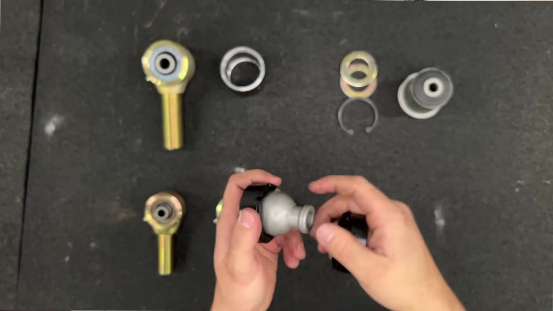 Hands demonstrating the ball center and independent crush sleeve of a Johnny Joint showing multi-axis rotation