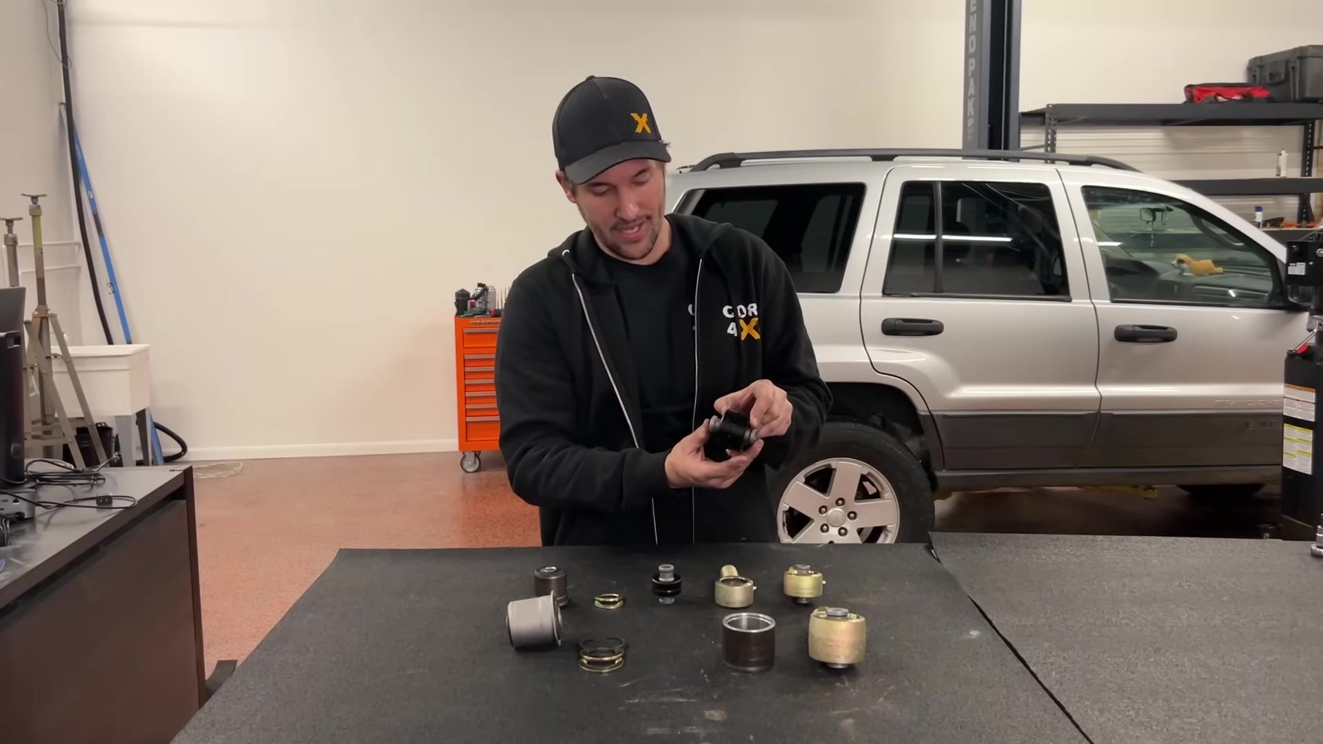 Spence holding a control arm at Core 4x4 explaining how the Johnny Joint integrates into Core product lines