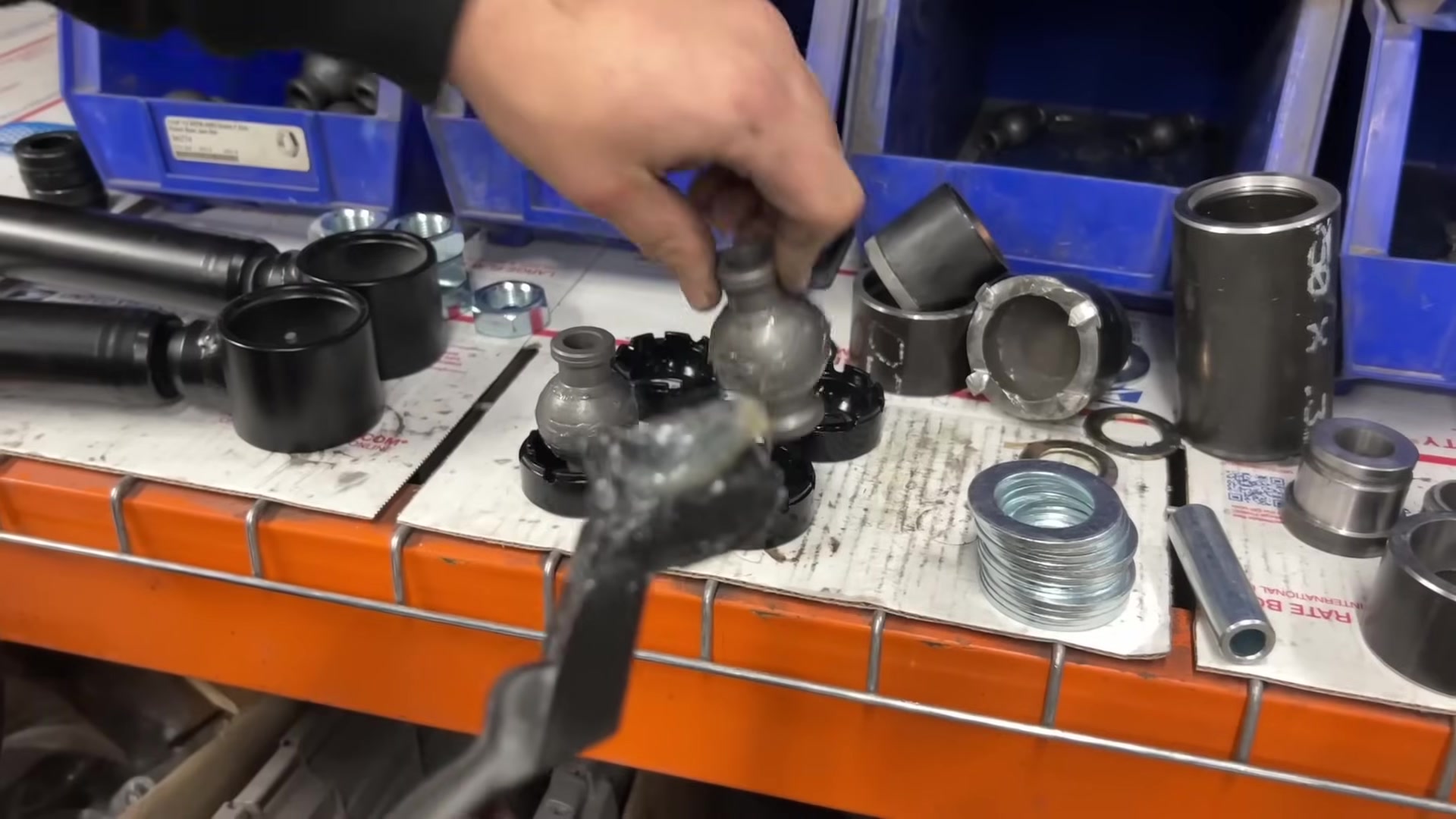 Workbench showing used Johnny Joint components including ball center, bushings, washers, and snap ring alongside rebuild parts
