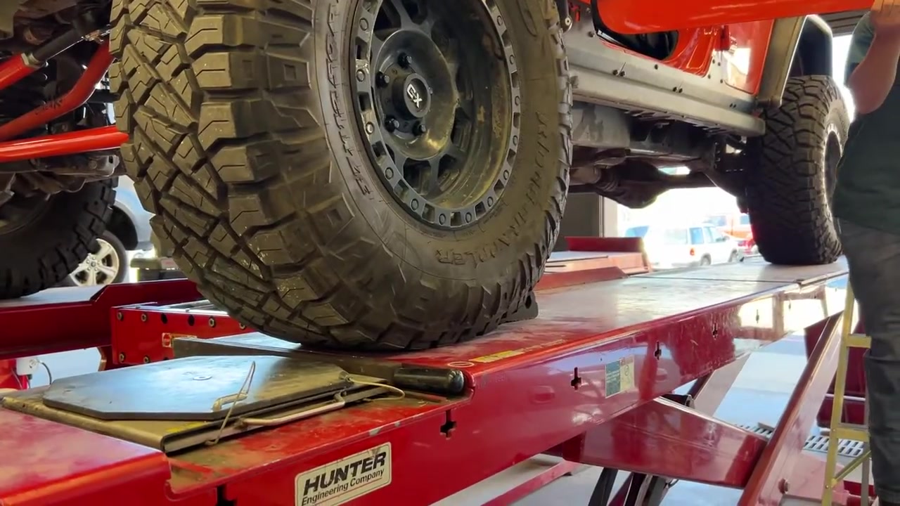 Close-up of the JL Wrangler front tire on the Hunter alignment rack with Core 4x4 red control arms visible underneath