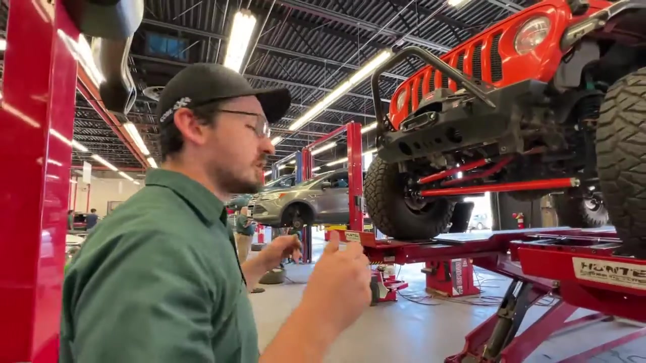 Trevor reading the alignment screen on the Hunter machine while adjusting the JL Wrangler front end