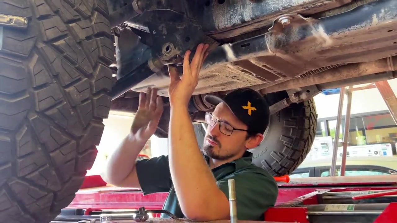 Trevor working underneath the JL Wrangler adjusting tie rod and steering components during alignment