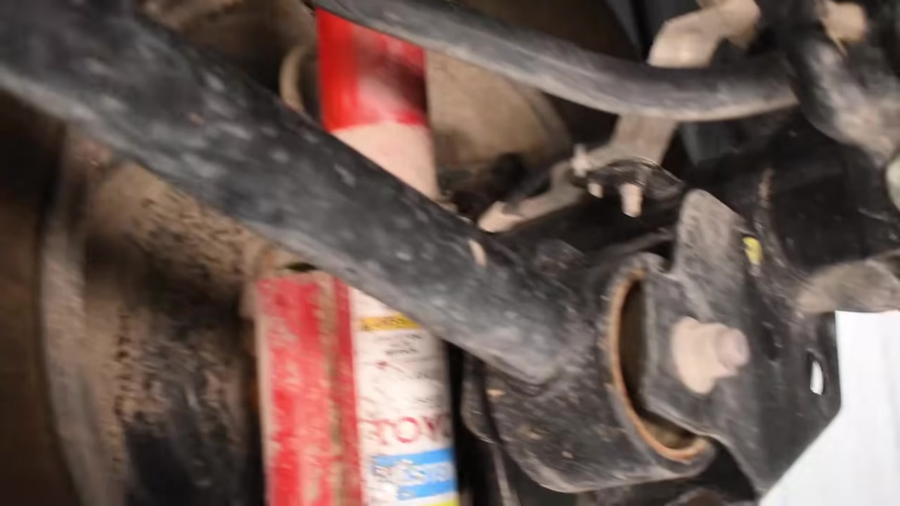 Underside view of factory control arms and shock absorber on a solid axle Jeep in the Core 4x4 shop