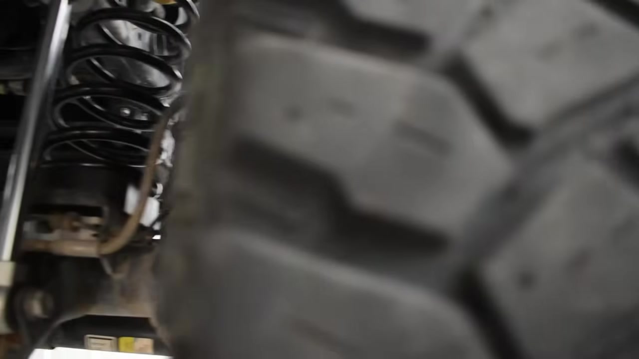 Underside view showing coil spring and suspension components on a lifted Jeep