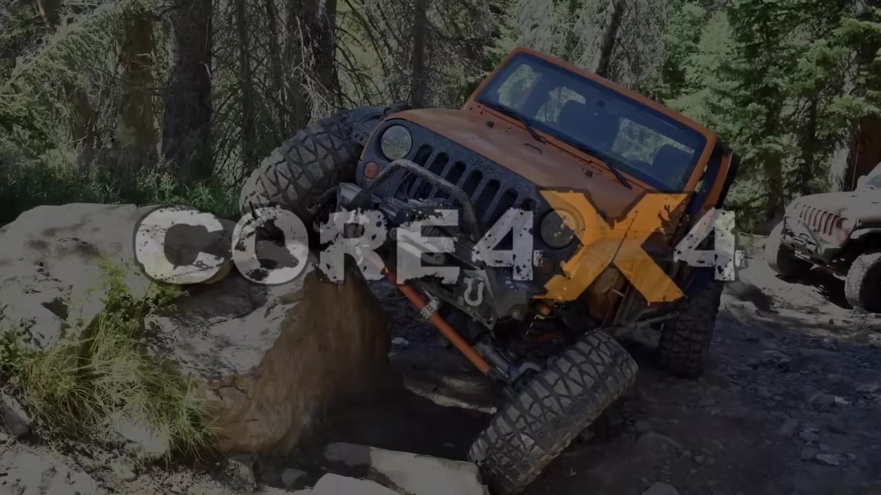 Orange Jeep Wrangler on a rocky trail demonstrating suspension articulation with Core 4x4 components