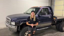 Gabby from Core 4x4 standing in front of the 1999 Dodge 3500 dually work truck in the Core 4x4 shop