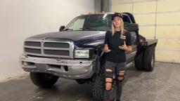 Gabby standing next to the lifted 1999 Dodge 3500, showing the front suspension area before the install