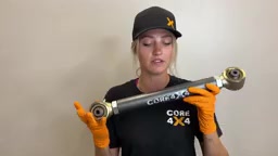 Gabby holding a new Core 4x4 Tier 4 adjustable control arm, showing the forged ends and Johnny Joints