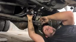 Under the Dodge 3500, installing the adjustable track bar between the frame and axle