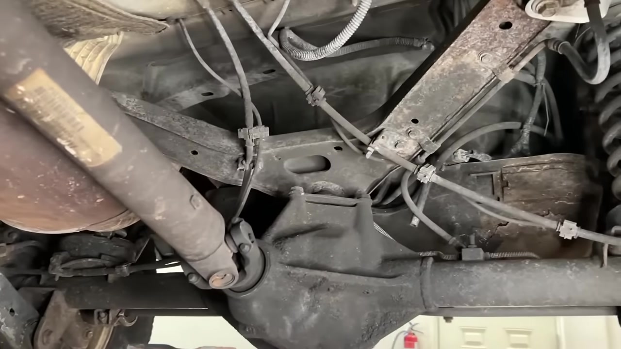 Under the WJ Grand Cherokee showing the factory rear upper A arm area with worn rubber ball joint and aging suspension components