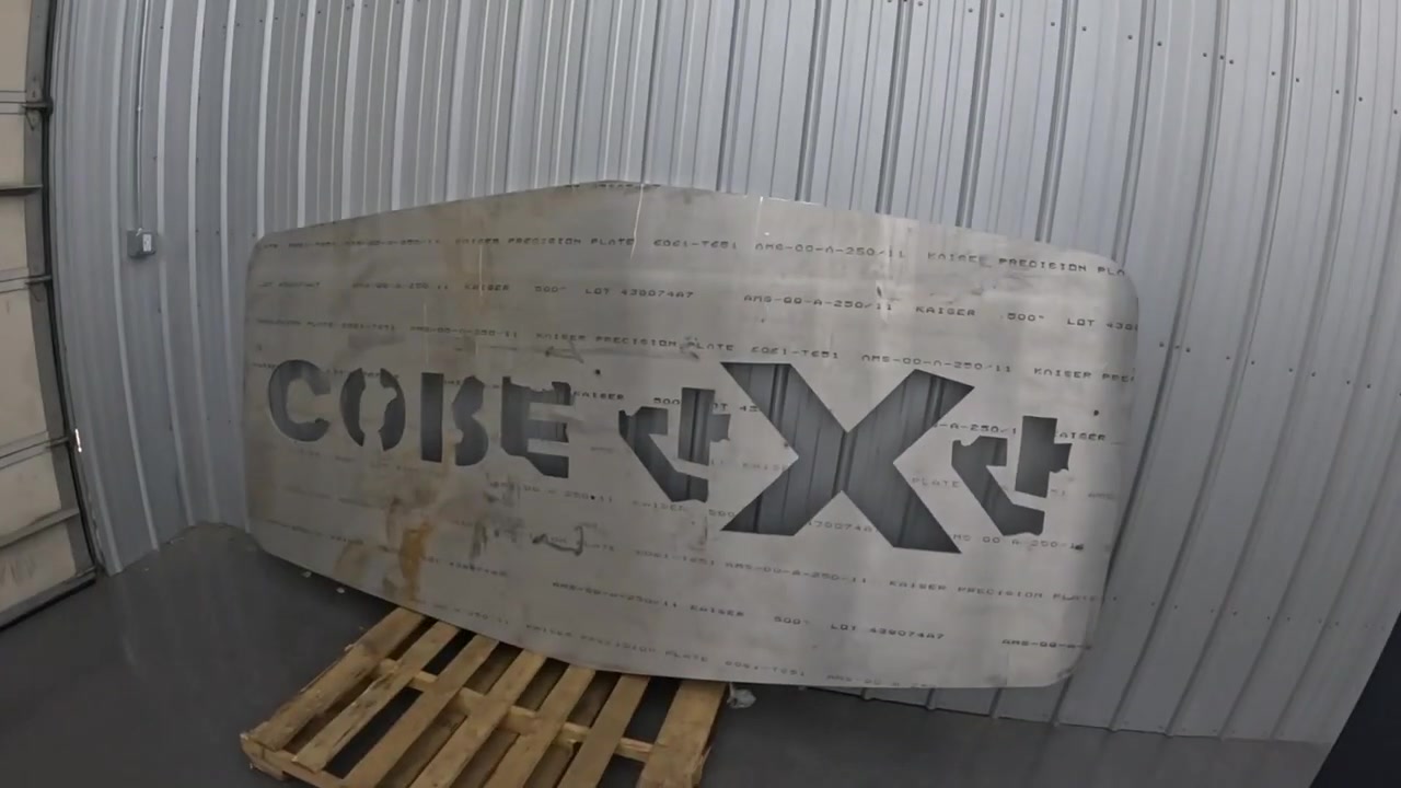 Half-inch aluminum slab with Core 4x4 logo laser-cut into the surface, leaning against the shop wall on a pallet