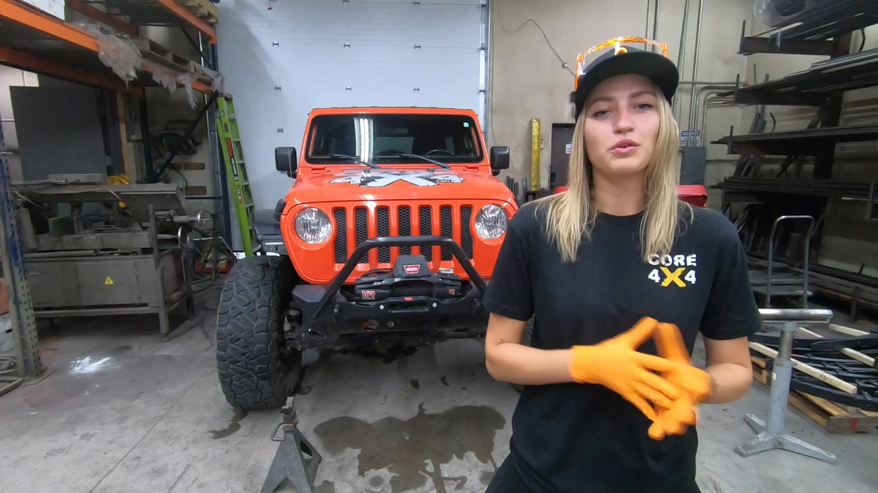 Gabby at Core 4x4 standing next to the orange JL Jeep Wrangler in the shop before the steering kit install