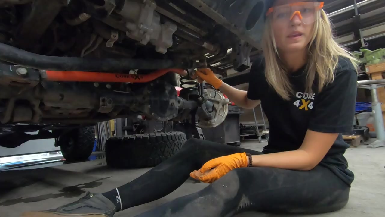 Gabby working underneath the JL Wrangler removing the factory drag link with a wrench